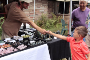 Vendor hands rock to child.