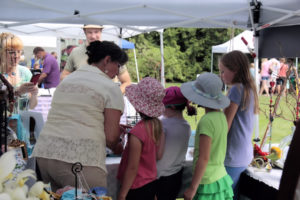 Children explore a vendor's exhibit and goods at Summer Fest.