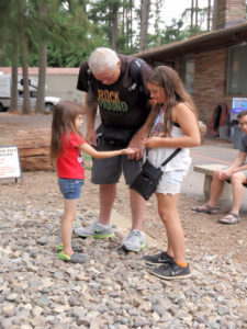 Children play in the rock pile with an adult at Summer Fest.