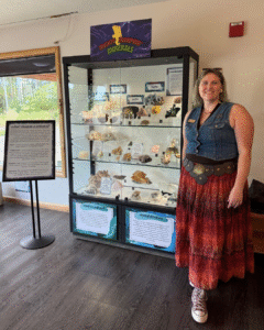 Addie smiling at the camera and standing beside the Mighty Morphin' Minerals exhibit.